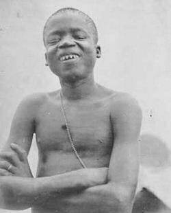 Photograph of Ota Benga Black and white archive photo of young African man shirtless and smiling with his arms crossed